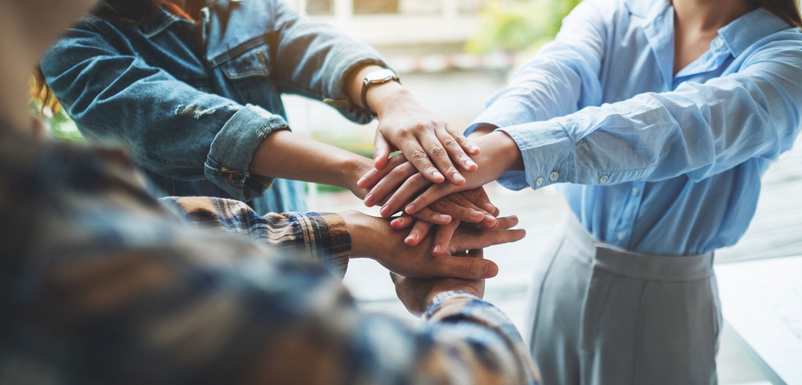 Closeup image of business team standing and joining their hands together in office © Adobe Stock